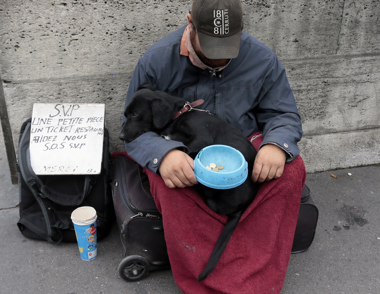 Bezdomovec sedí na ulici se psem na klíně