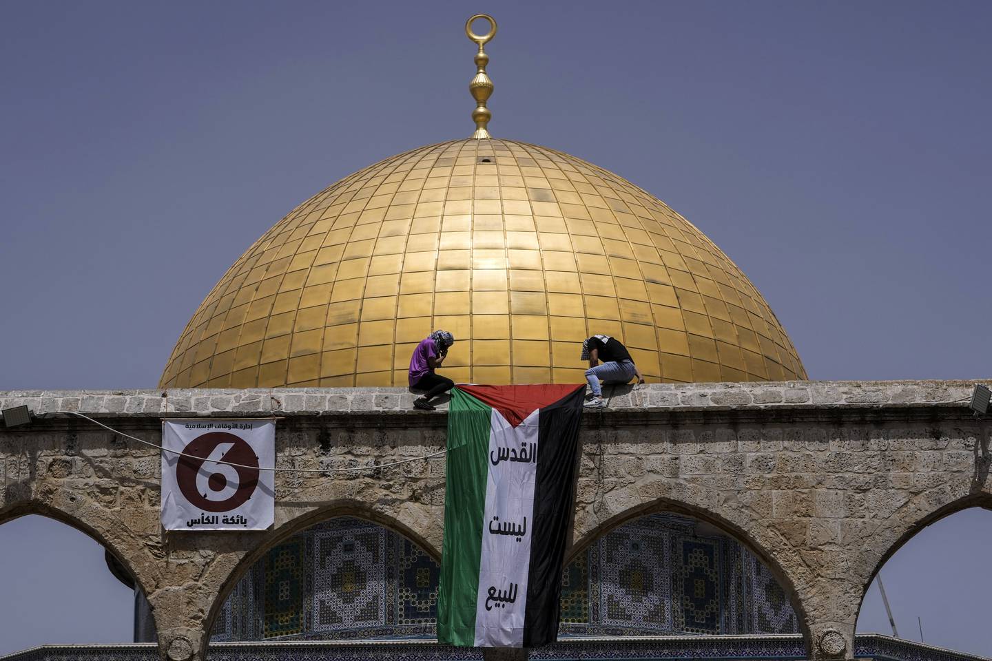 Maskovaní Palestinci vyvěšují státní vlajku během ramadánu v dubnu před svatyní Dome of the Rock v areálu mešity Al Aksá v jeruzalémském Starém městě.